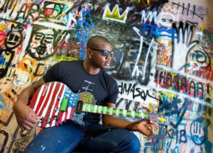 Man wearing shades playing a guitar